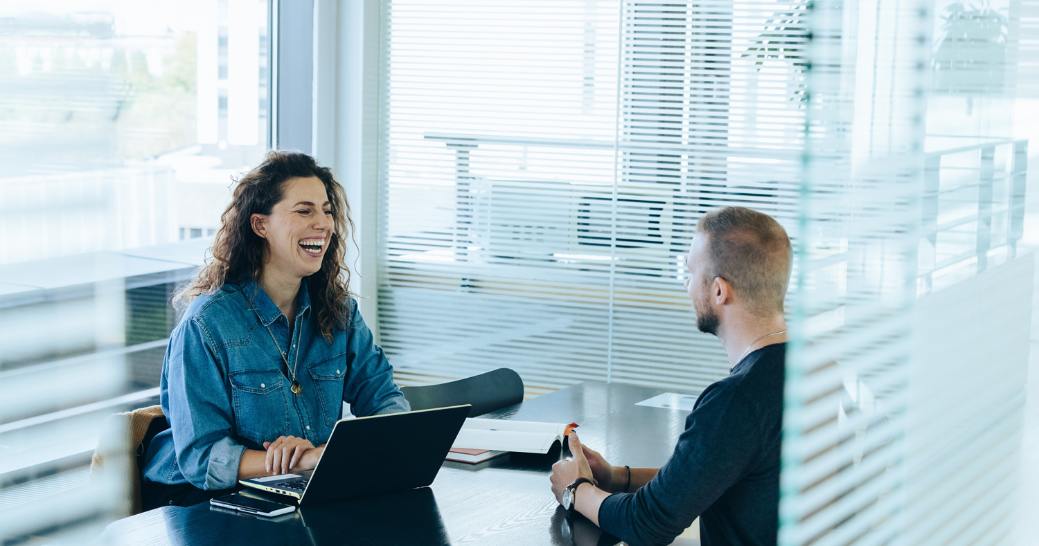 Foto von einem Mann und einer lachenden Frau, die sich gegenübersitzen